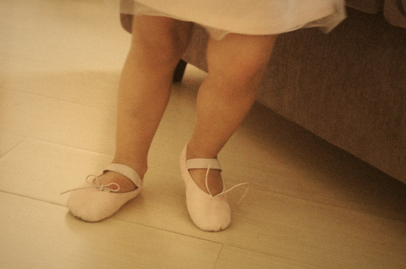 Pies de una niña con medias puntas rosas sobre un suelo de madera