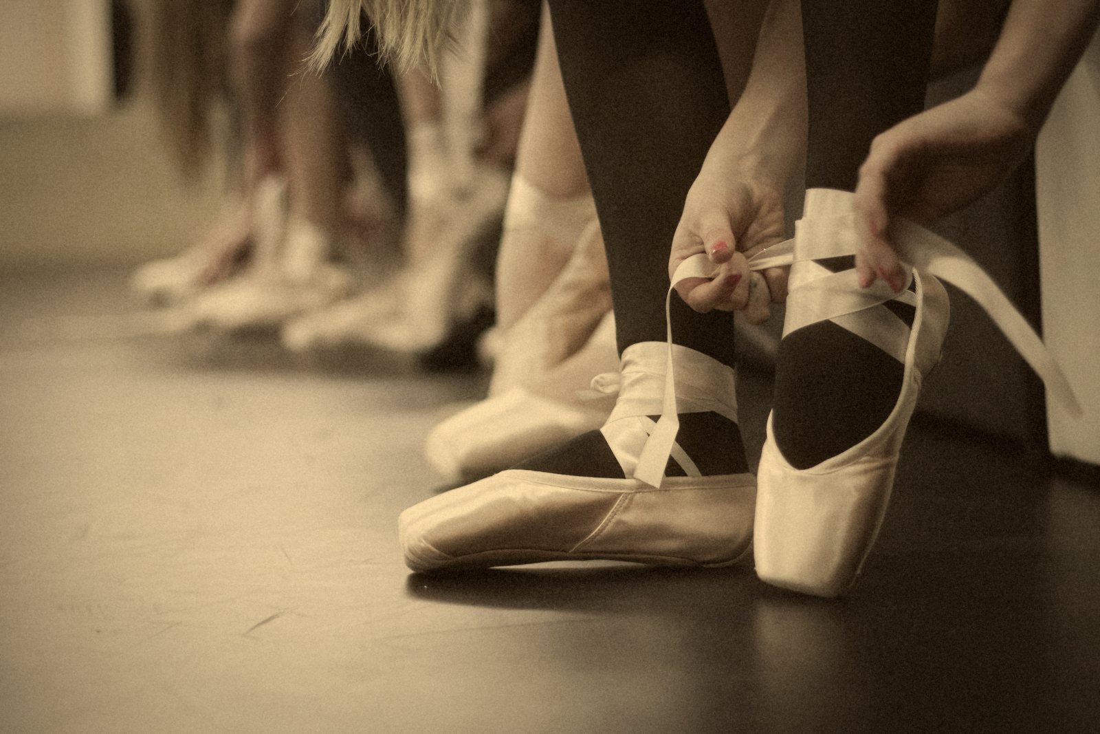 Bailarinas sentadas en el suelo atándose las puntas