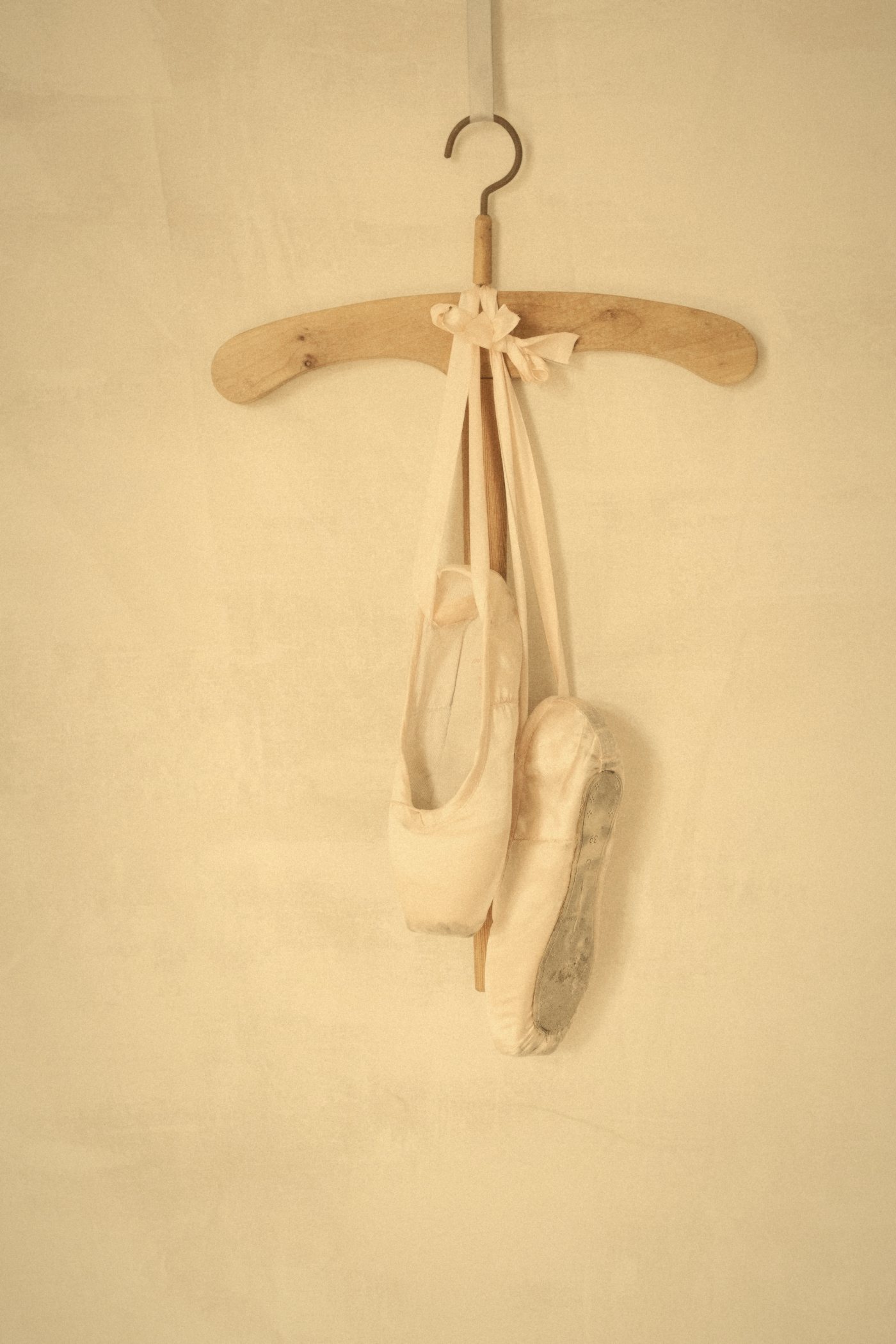 Par de puntas colgadas de una percha de madera por las cintas