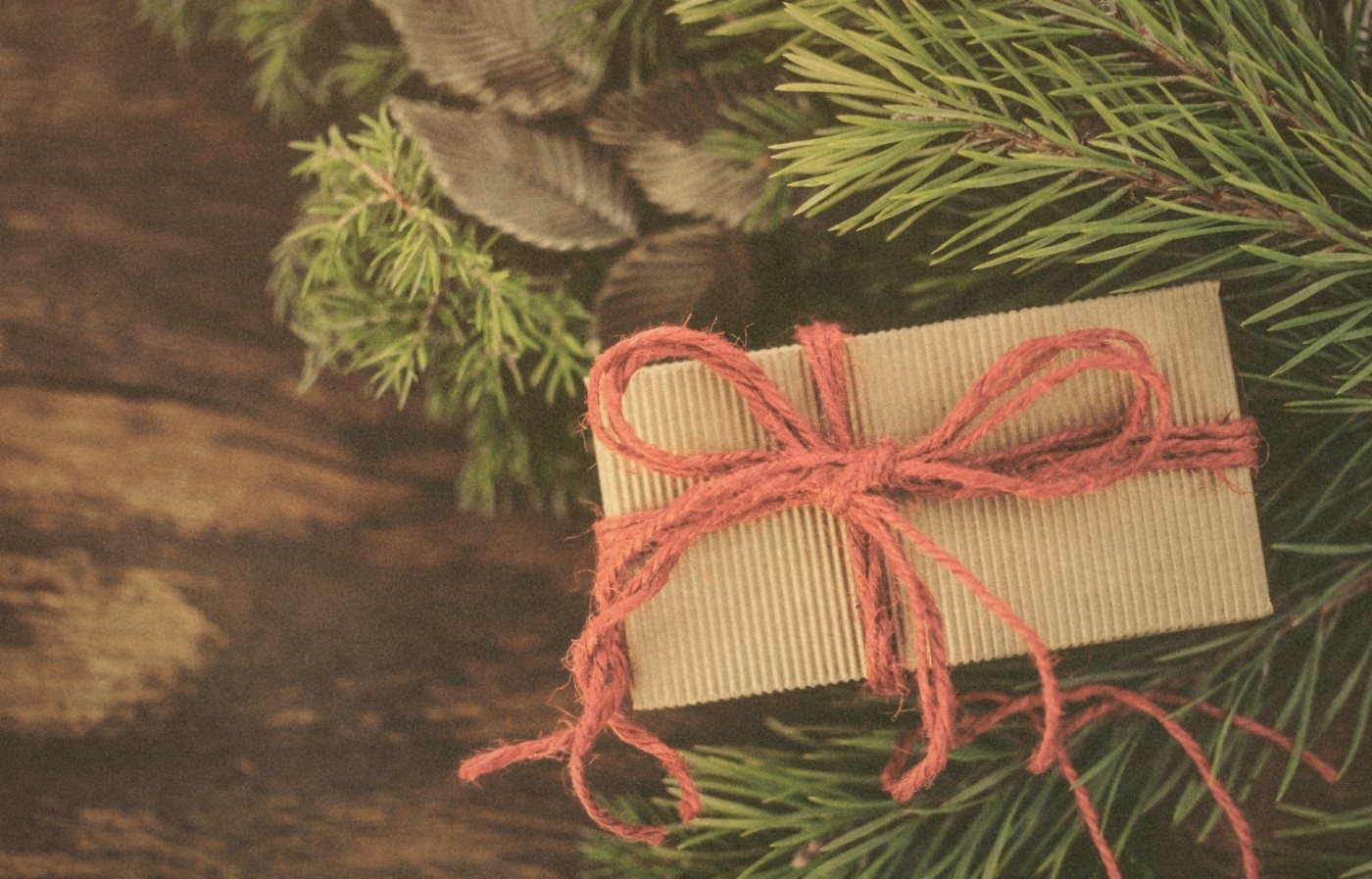 Regalo envuelto en papel kraft con cordel rojo y ramas de abeto