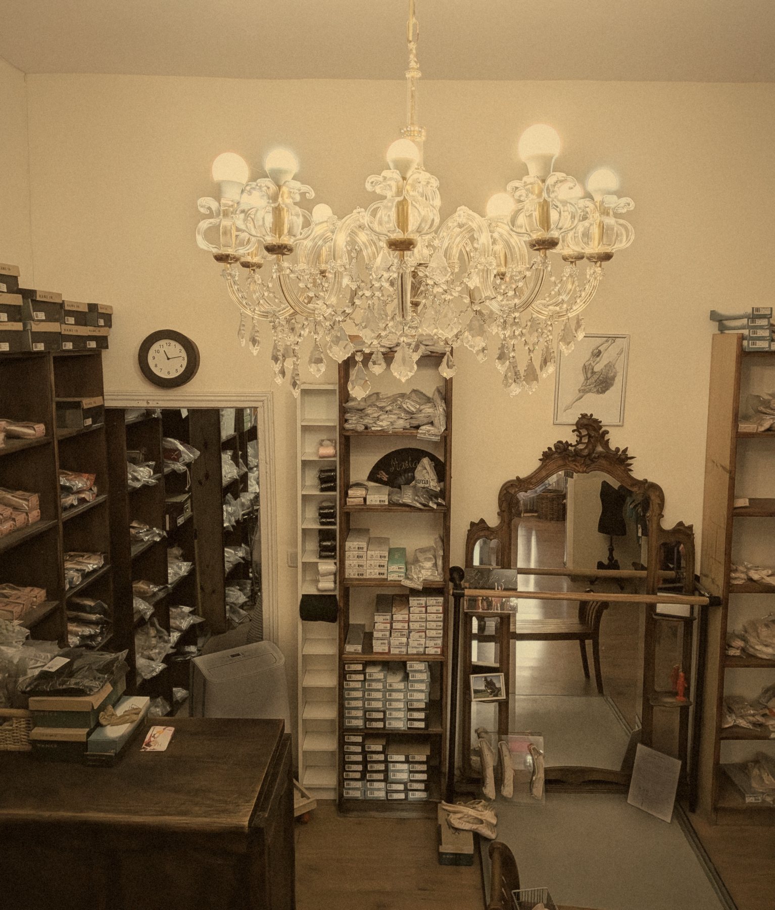 Interior de la tienda Mi Favorita, con una lámpara de araña, estanterías de madera con cajas de puntas y un espejo antiguo