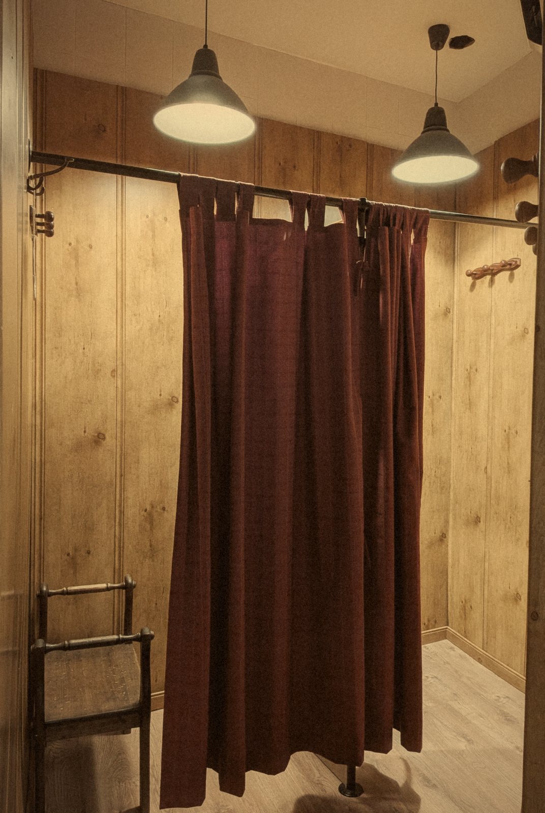 Probador de la tienda, con una cortina oscura y paredes de madera